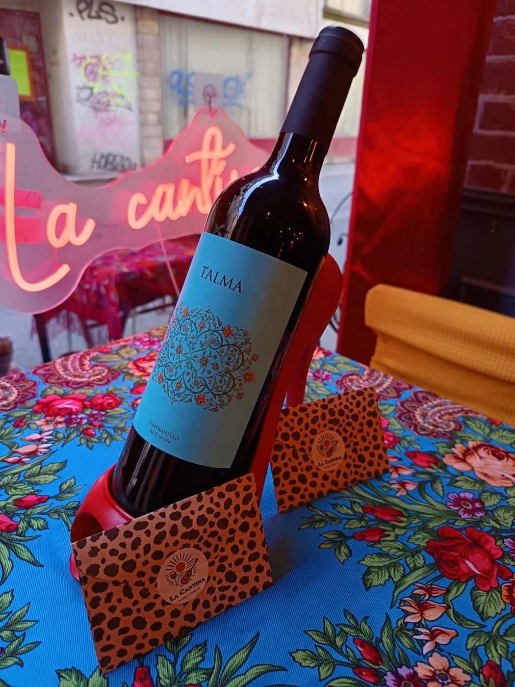 Bouteille de vin espagnol dans un escarpin rouge sur la nappe à fleurs